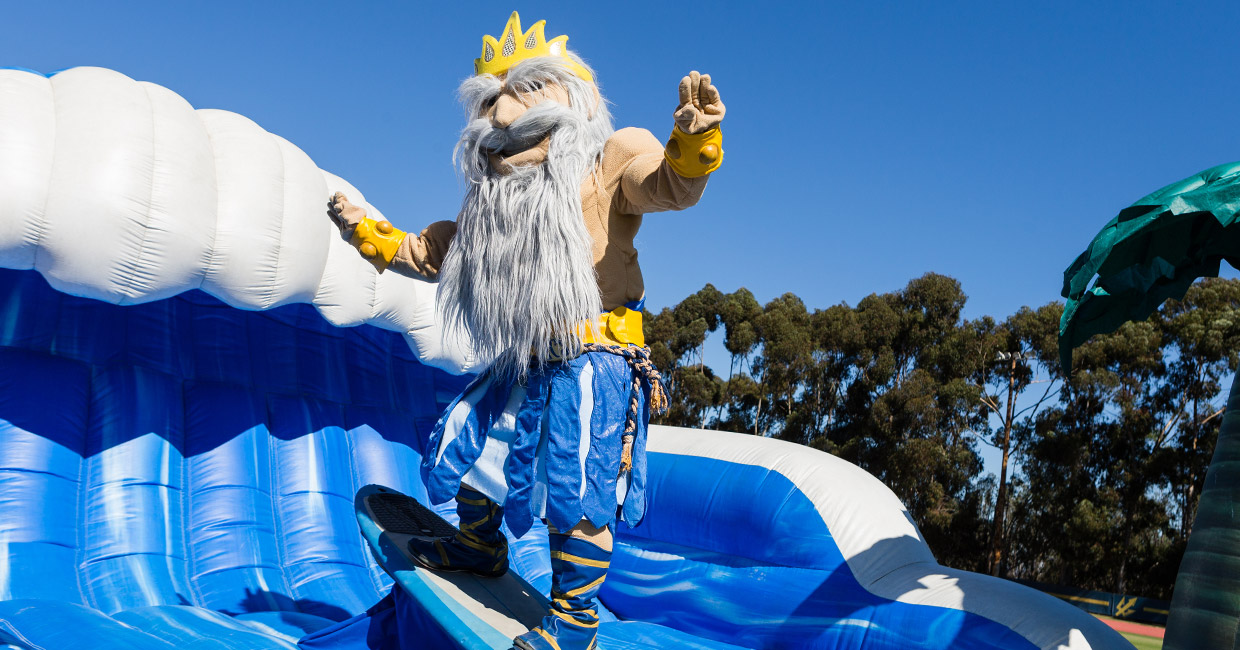 King Triton mascot surfing on a blow up wave