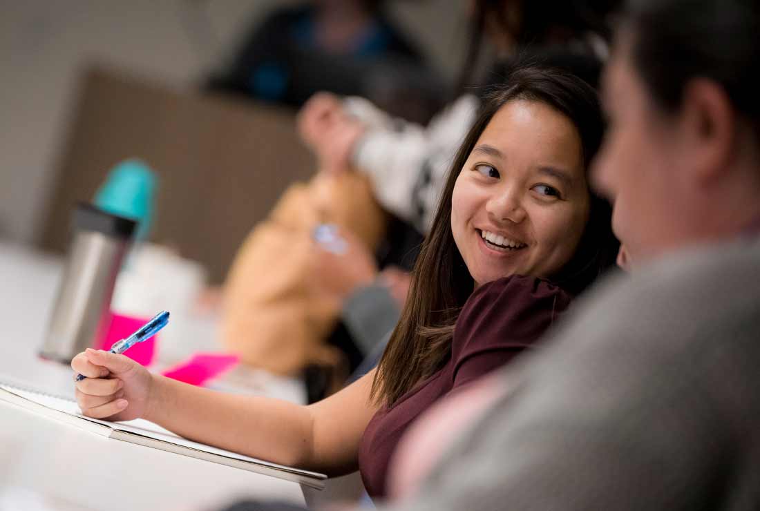Girl smiling and taking notes in class