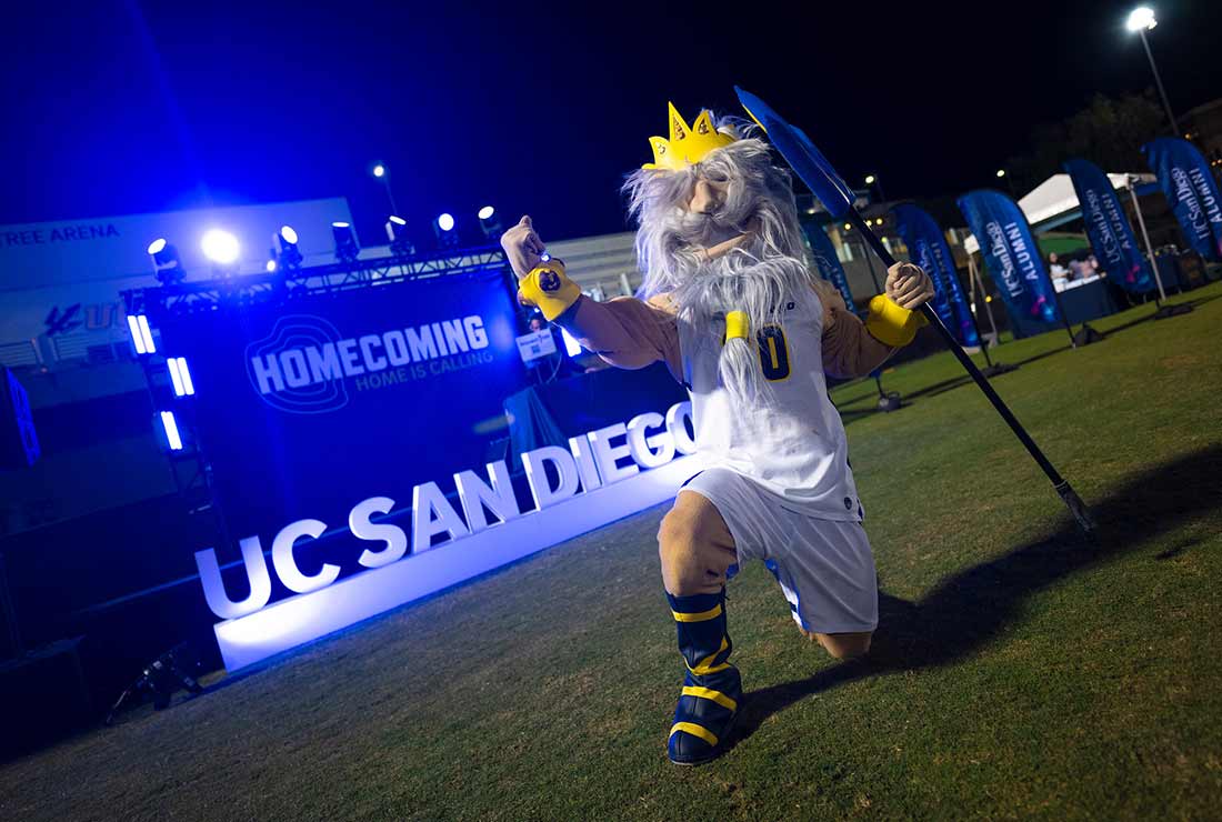 King Triton posing in front of Homecoming banner